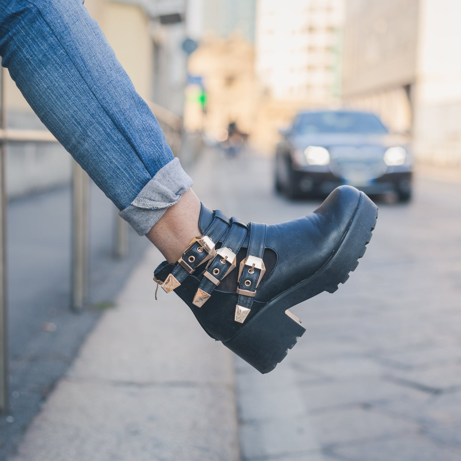 Person wearing blue platform boots with buckles on a city street.